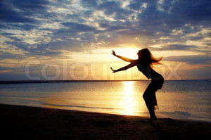 Active woman dancing at the beach during sunset, stock photo