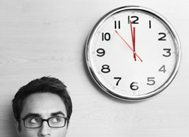 This is a photo of a ticking clock and a man looking at it.