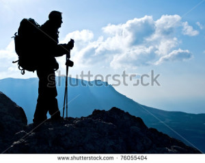 Hiker on top, silhouetted in high mountains