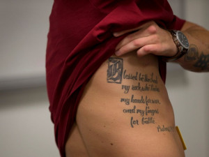 ... to show a tattoo on his side as he speaks with media at the Pentagon