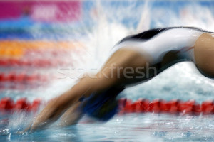 woman backstroke swimmer dives into the pool at the start of a race