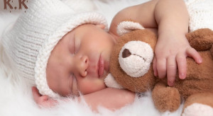 Sleeping newborn baby hugging teddy bear