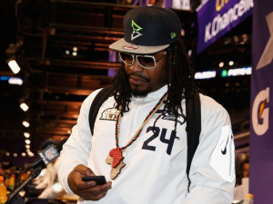 looks at his phone at Super Bowl XLIX Media Day on January 27, 2015 ...
