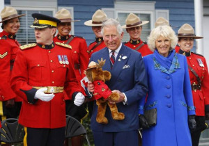 Prince Charles holds a stuffed toy moose beside his wife Camilla ...