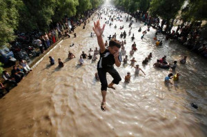 boy jumps into a water canal to cool himself with others on a hot ...