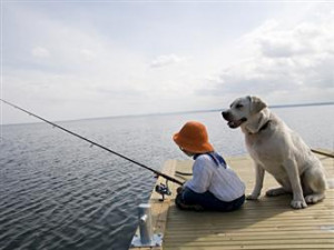 Little girl fishing, with a yellow labrador retriever at her side