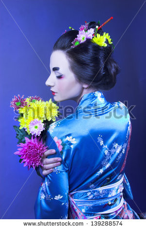 ... Young woman in blue kimono and with flowers in her hair. - stock photo