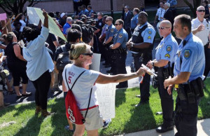 Protesters try to present packages of food to police officers who were ...