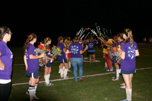 Field hockey players create a tunnel for the seniors to run through.