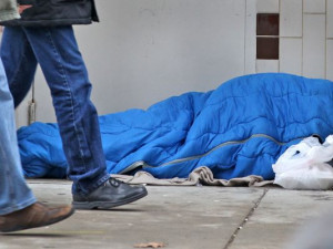 People walk past a homeless person sleeping inside a doorway on ...