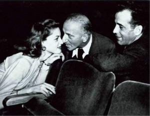 Lauren Bacall gets the Jimmy Durante nose smooch while Bogart appears ...
