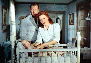 John Wayne and Maureen O'Hara stand over a baby in a crib in a scene ...