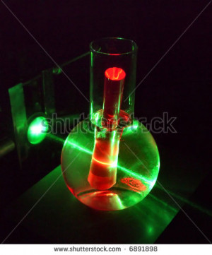 green laser beam running through water and ruby rod - stock photo