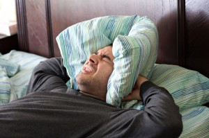 picture of A man having trouble sleeping squeezes a pillow around his ...