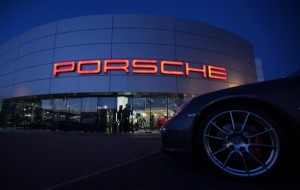 An illuminated Porsche logo is pictured on a Porsche retail dealership ...