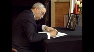 Colin Powell writing on a book, courtesy of AP Graphics