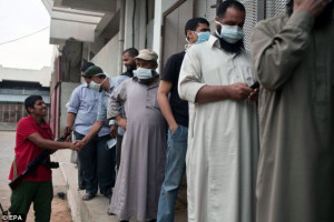 ... masks as they wait in line to visit Muammar Gaddafi's body in Misrata