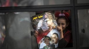holds a poster with a portrait of late president Gamal Abdel Nasser ...