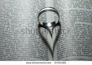 Wedding ring casting a heart onto a bible. 