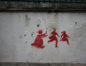 Graffiti on a wall in Lisbon depicting a priest chasing two children.