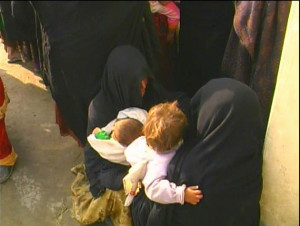 Afghan women crouch with babies by Tim King