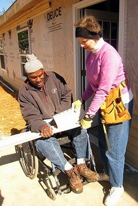 Linda Fuller and Thaddeus Harris hang siding together on his new home.