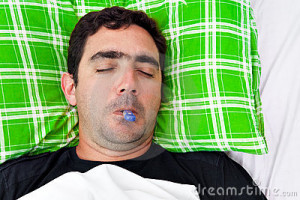 Portrait of a sick hispanic man laying in bed with a thermometer in ...