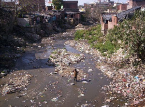 Figure 9: Child in slum stands in garbage filled stream (Meg & Rahul ...