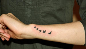 small flying birds silhouette tattooed on forearm and wrist