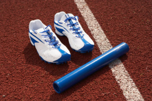 Relay baton and sports shoes on track, elevated view