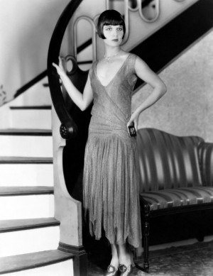 fashionable Louise Brooks striking a pose by her stairway in 1925