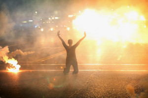 Tear gas surrounds a woman kneeling in the street with her hands in ...