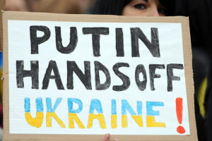 demonstrator holds a poster reading ‘Putin, Hands off Ukraine ...