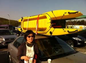 kayak angler drinking coffee next to 2 car topped fishing kayaks