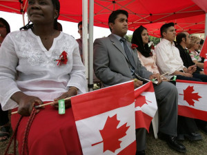 People hold Canadian flag prior to becoming Canadian citizens at a ...