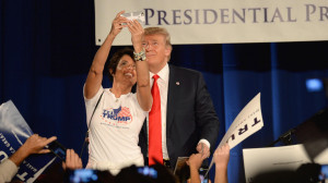 Donald Trump poses for a selfie with a woman wearing a 