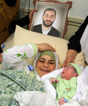 new born son as she lays under a photograph of her imprisoned husband ...