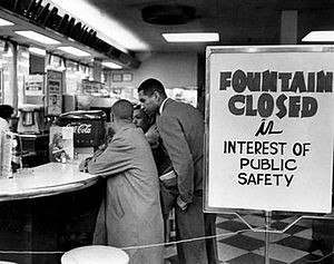 Lunch counter with four young black men seated at bar stools along the ...