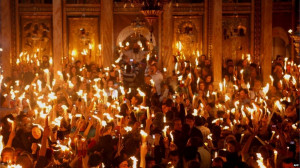 Christian Orthodox worshippers hold up candles lit from the 