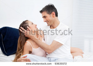 Happy married couple cuddling in their bed - stock photo