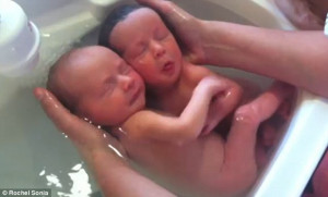 ... twins cling to each other as they are bathed for the very first time