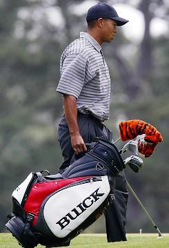 Tiger Woods carries his golf bag across the third tee during a ...