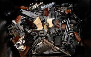 pile of handguns are placed in a trash bin after they were ...