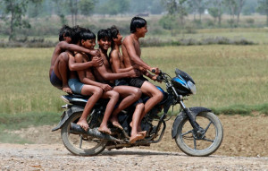 Boys ride a motorbike on their way back home after taking a bath in a ...