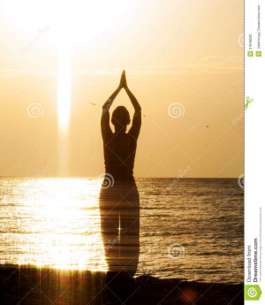 Woman doing yoga on the beach in the morning sunrise. Greating a sun.