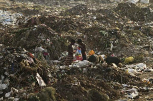In this June 12, 2014 photo, children look inside a plastic bag as ...