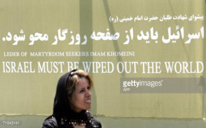 An Iranian woman walks past a banner repeating the famous quote by the ...