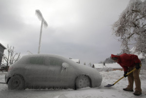 ... man shovels ice next to ice-covered car in Postojna February 3, 2014