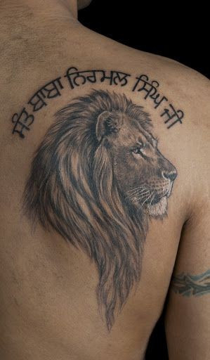 Lion head with inscription tattoo on shoulder blade