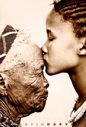 Young San girl kissing old woman on forehead.
